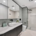 Modern bathroom design featuring a sleek vanity with a round basin, stylish cabinetry, and a glass shower, showcasing a contemporary aesthetic ideal for renovations by Cornerstone Property Group.
