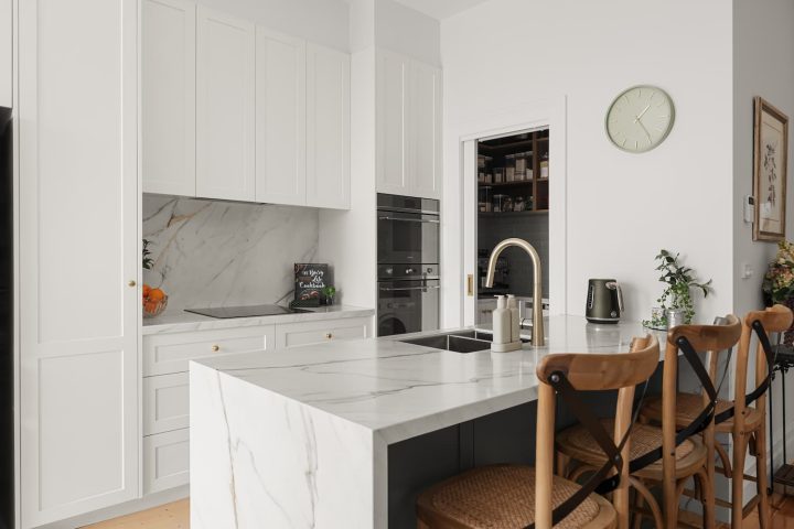 Modern kitchen featuring white cabinetry, marble island, and stainless steel appliances, highlighting home renovation design elements relevant to Narelle's insights at Cornerstone Property Group.