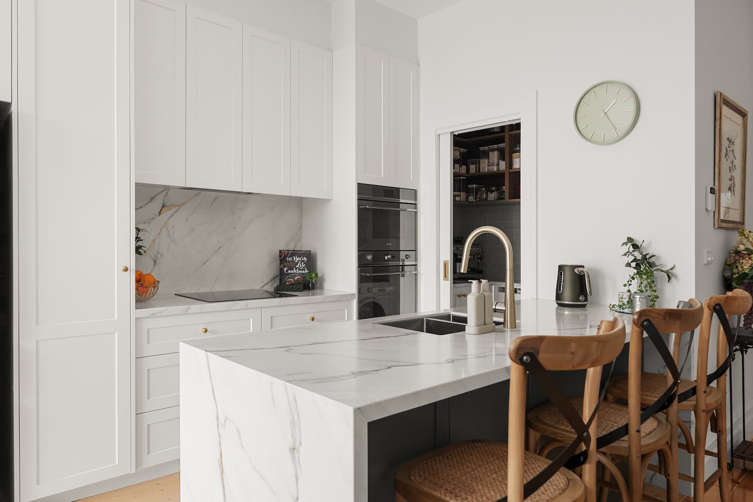 Modern kitchen interior featuring white cabinetry, marble countertops, and a stylish sink, designed for Melbourne renovations by Cornerstone Property Group.