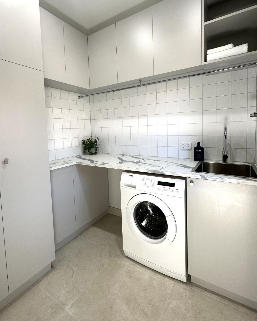 Modern laundry renovation featuring sleek cabinetry, marble countertop, washing machine, and stainless steel sink, showcasing functional design for Melbourne homes.